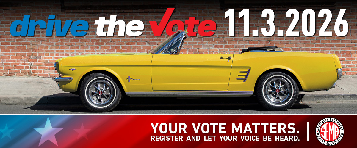 Mustang parked in front of a brik wall. Drive the Vote message.