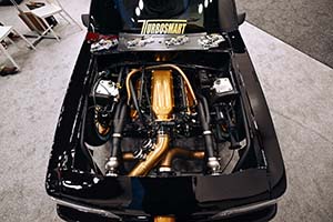 Race engine with gold colored intake manifold and tubing installed in black car