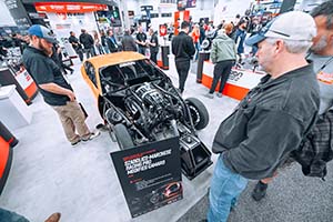 Three men looking at orange Pro Mod race car with black engine