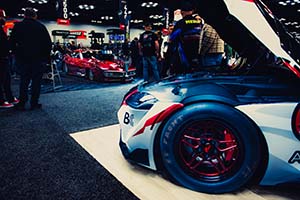 Front corner of race car with tire and red race car in background