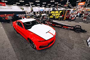 Red and white Camaro on left with black dragster on right