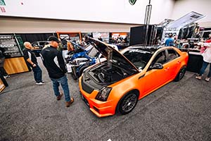 Man looking at orange Cadillac with hood open