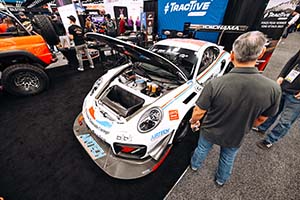 Man looking at white Porsche with front hood open