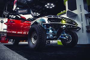 Race truck with red passenger side door open and lights illuminating the engine bay and suspension