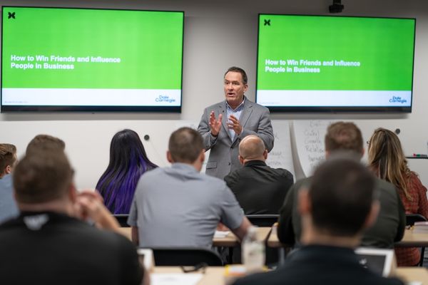 Man presenting in a classroom setting - How to Win Friends and Influence People in Business.