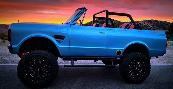 Blue Ford Bronco chop top on raod at sunset